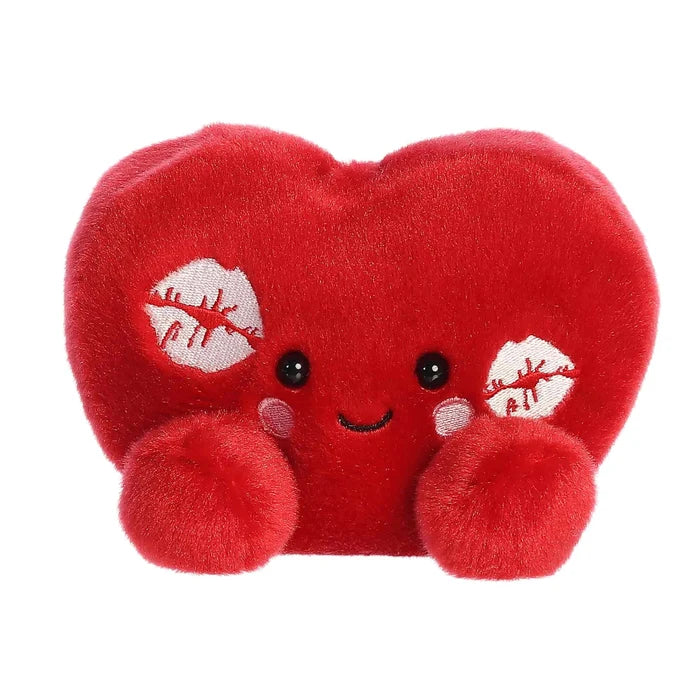 A red heart-shaped pillow adorned with various lipstick kisses, symbolizing love and affection.