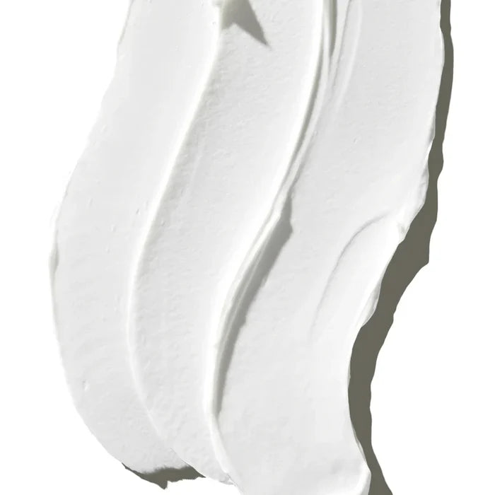 A dollop of white cream placed on a white surface, creating a subtle contrast.