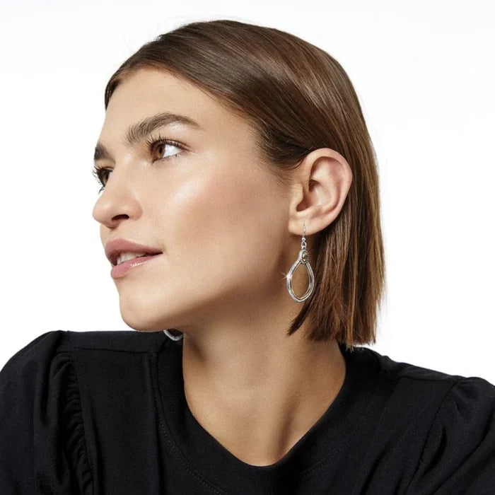 1. A woman in a black top and earrings, looking confidently at the camera.