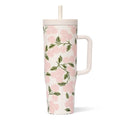 A pink and green floral print mug with a straw, featuring vibrant flowers against a light background.