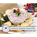 A jar of cranberry jalapeño spread mix, showcasing a vibrant red color with visible jalapeño pieces and spices.