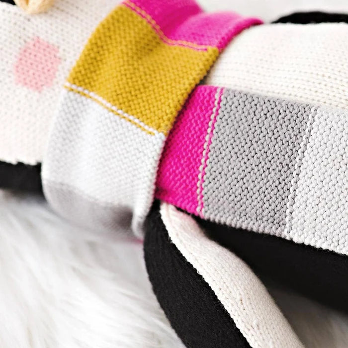 Detail of Aspen the Penguin’s multicolored knit scarf in yellow, gray, pink, and white stripes.