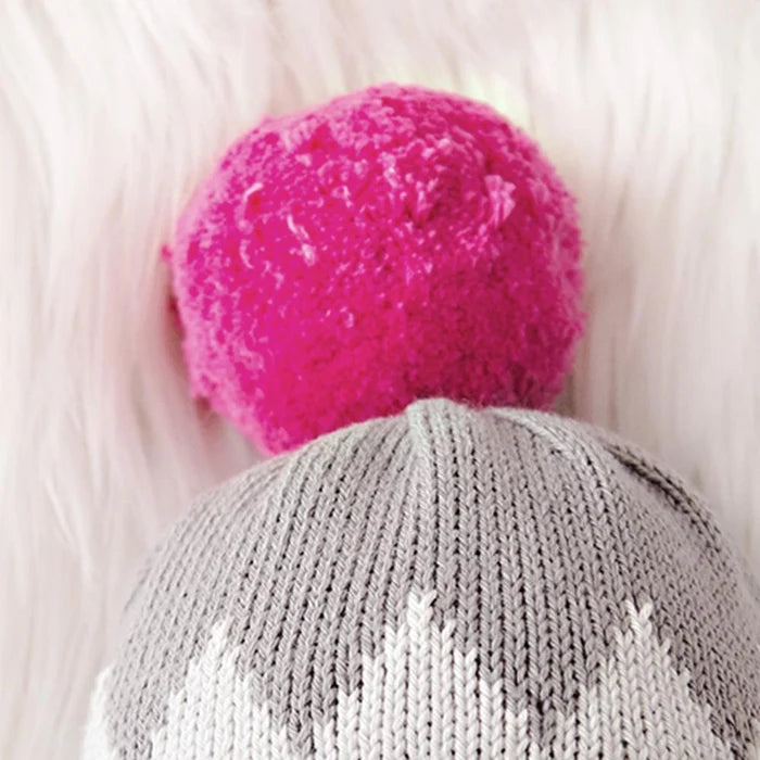 Close-up of Aspen the Penguin’s gray knit winter hat with a bright pink pom-pom detail.