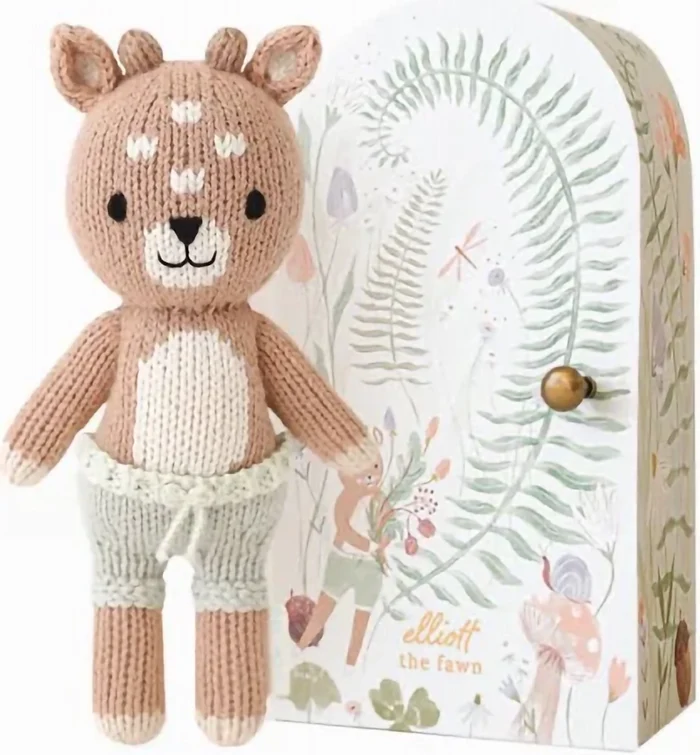 Tiny Elliott the Fawn knit doll standing next to illustrated Cuddle + Kind gift box