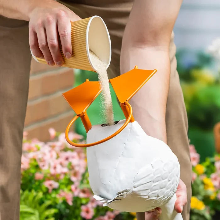 A decorative white goose statue is placed on a porch adorned with blooming flowers.