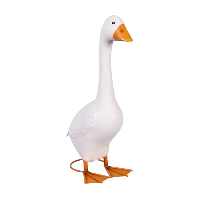 A charming white goose statue sits on a porch, framed by a variety of flowers.