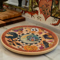 A round wooden Halloween-themed lazy susan board with colorful hand-painted illustrations of a cat, owl, spider, jack-o'-lantern, and bats, set on a kitchen countertop.