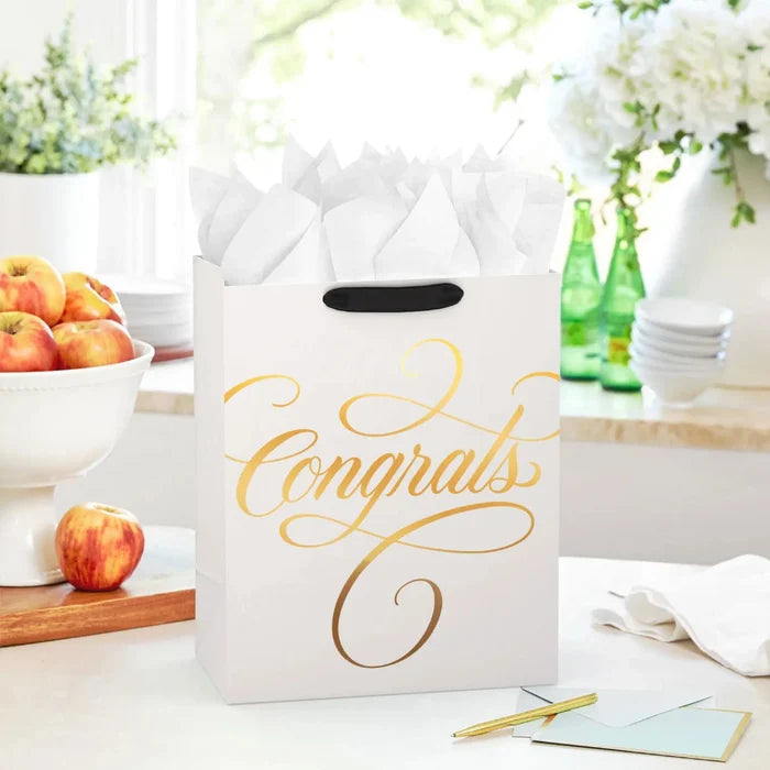 Elegant cream and gold “Congrats” gift bag styled on a tabletop with a matching celebration card