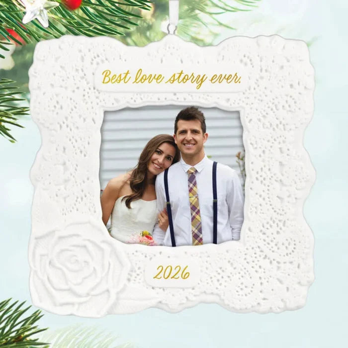 Decorative photo ornament with a couple's picture and 'Best love story ever' text, surrounded by Christmas tree branches.