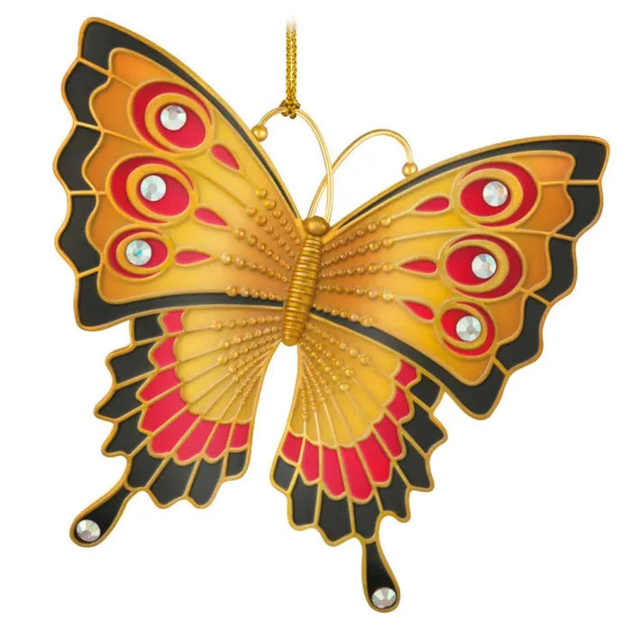 Decorative butterfly ornament with gold, red, and black colors on a white background