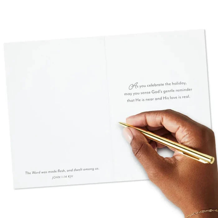 Hand holding a gold pen over a white card with text