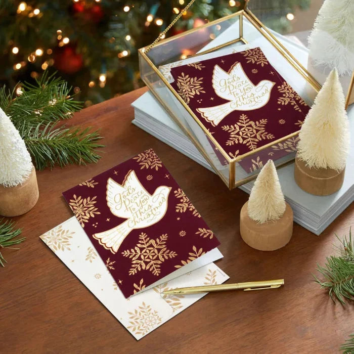 Decorative greeting cards with a dove design on a wooden surface with Christmas decorations.