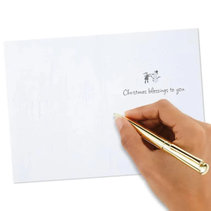 Hand holding a gold pen over a white card with 'Christmas blessings to you' text on a white background
