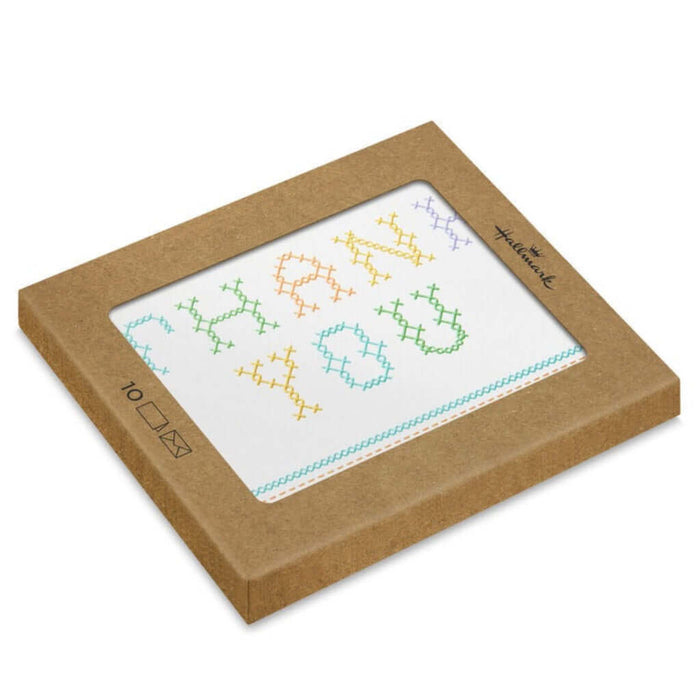 Cross-stitched designed thank you cards in a brown cardboard box on a white background