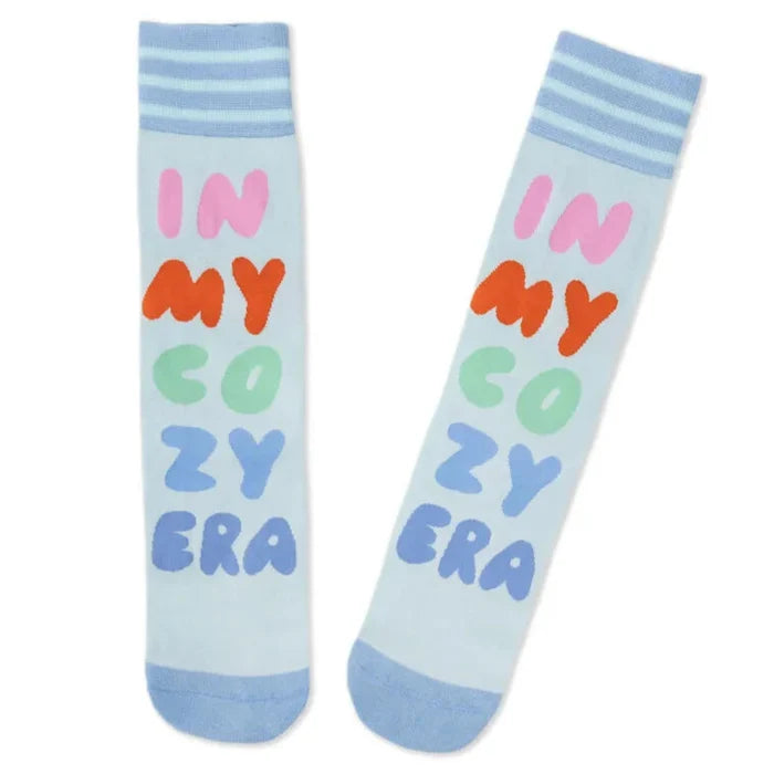 Light blue socks with colorful text 'IN MY COZY ERA' on a white background