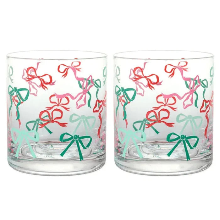 Two clear glass tumblers with colorful bow pattern on a white background