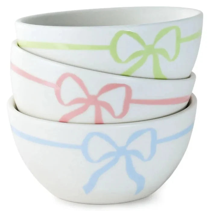 Set of three white bowls with colorful bow designs on a white background