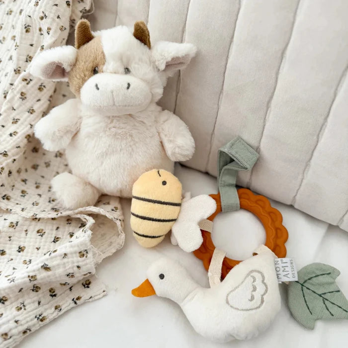 Plush cow sitting among other baby toys