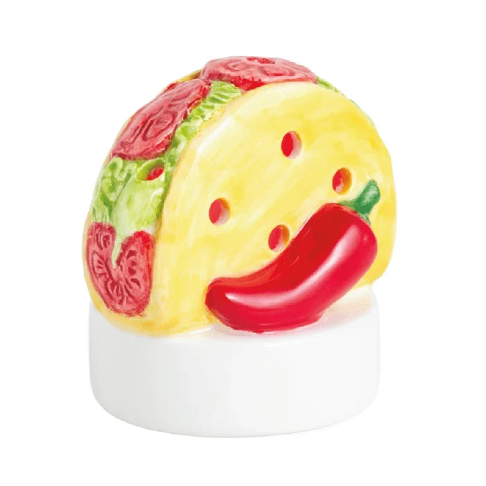 A taco-shaped candle holder beside a vibrant red pepper, showcasing a playful and colorful kitchen decor item.