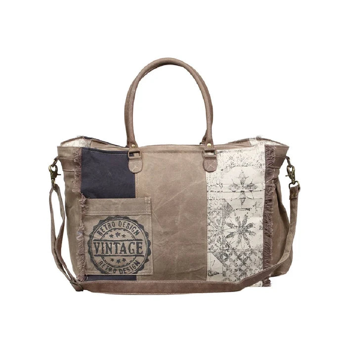 Vintage canvas bag adorned with various patches, showcasing a unique and eclectic style.