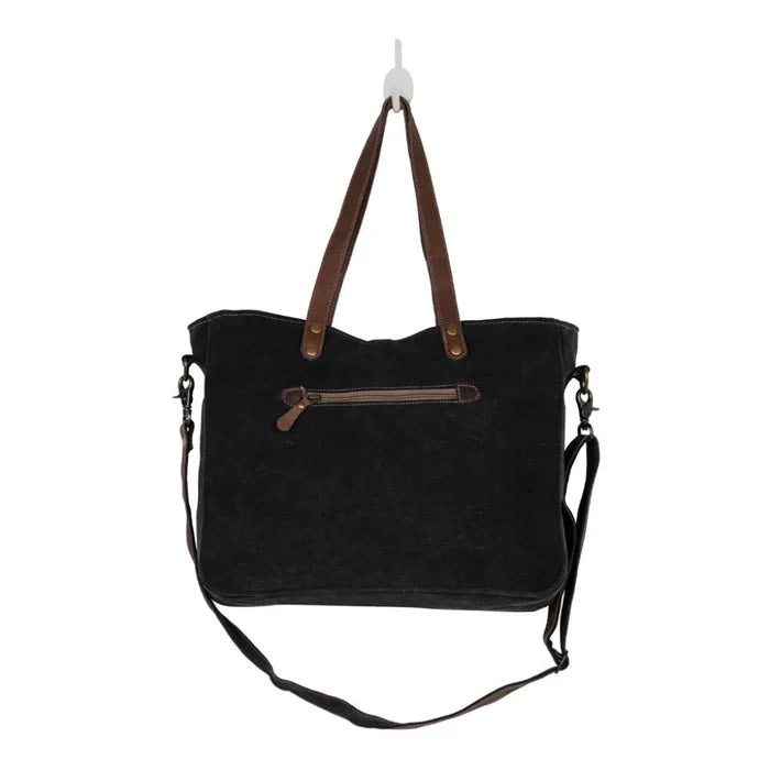 The Myra Bag Mystique Messenger Bag features upcycled woven canvas with rich leather accents.