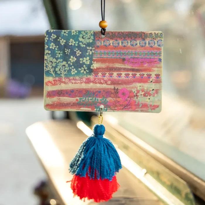 A tassel hangs from a window sill beside an American flag, symbolizing patriotism and home decor.
