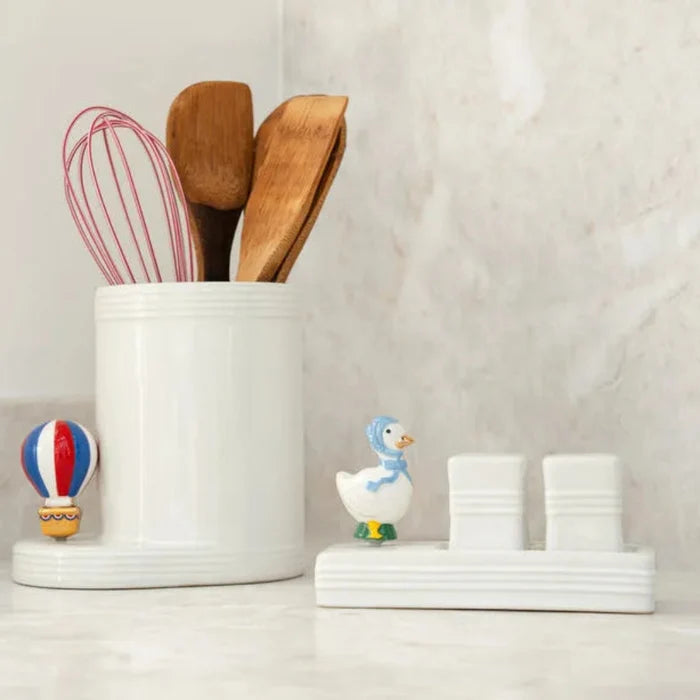 White container with wooden utensils and small  Mother goose mini figurines on a light background