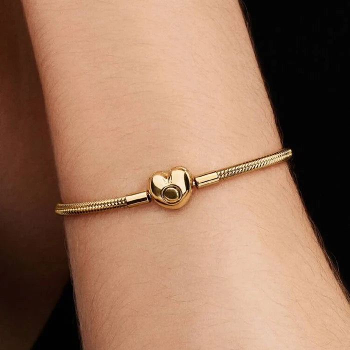 Gold-tone snake chain charm bracelet featuring a polished heart-shaped clasp on a white background, ideal for everyday wear and customizable with charms.