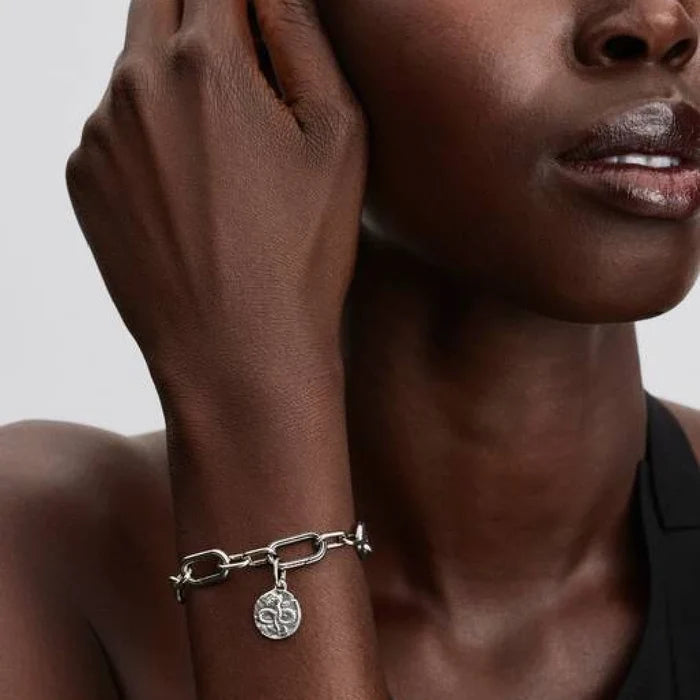 A silver bracelet with a unique charm hanging from it.
