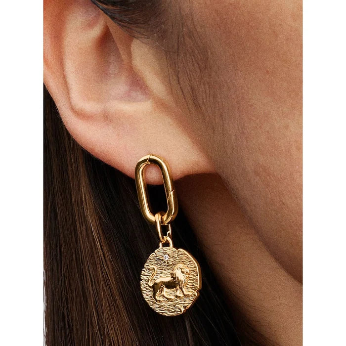 Close-up of Pandora gold earring with lion zodiac coin charm on textured link.