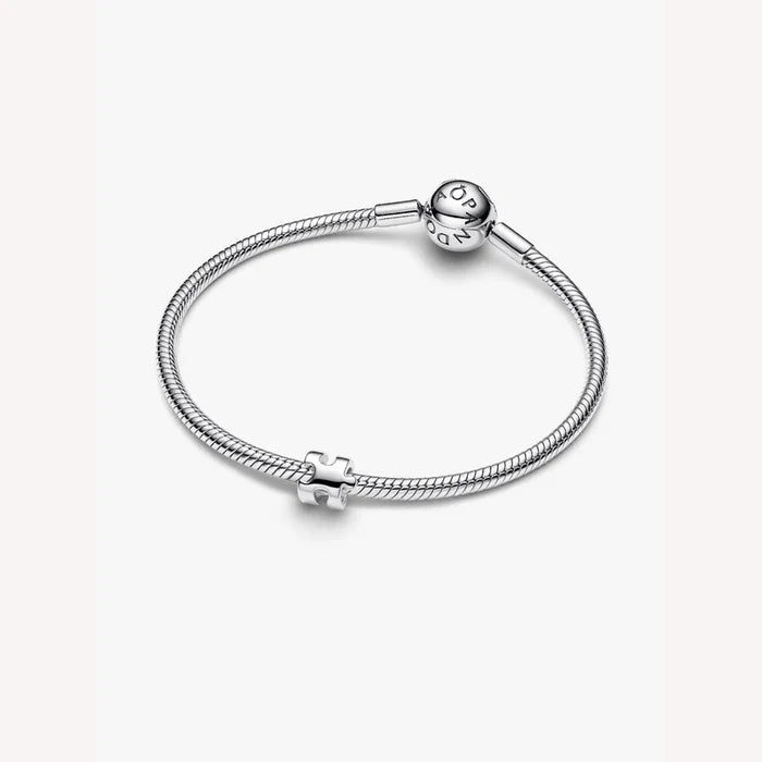 Silver bracelet with a puzzle piece charm on a light background