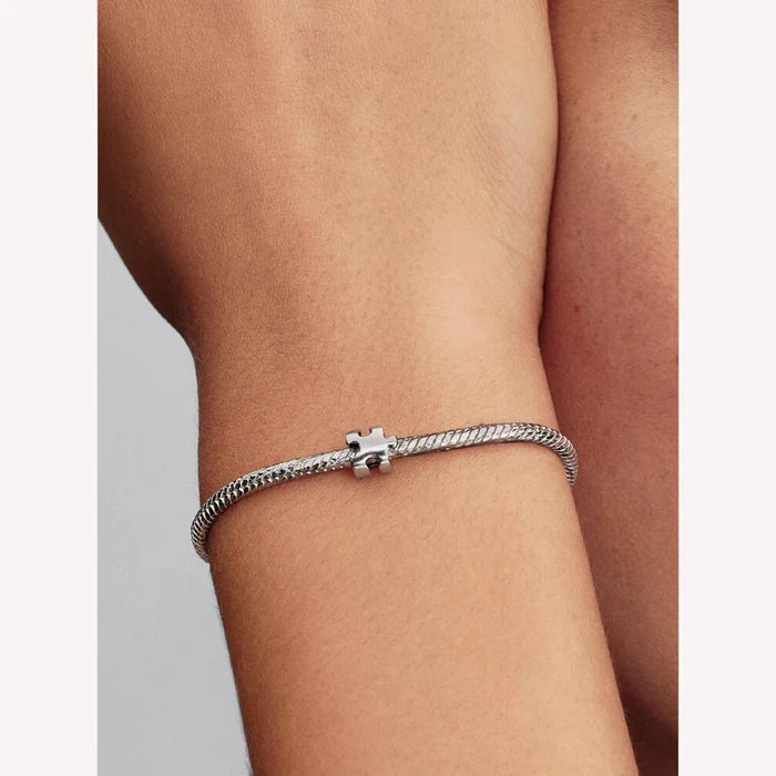 Silver bracelet with a puzzle piece charm on a person's wrist