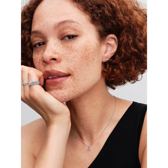Woman wearing Pandora Butterfly jewelry collection including a ring, earrings, and necklace on a plain background
