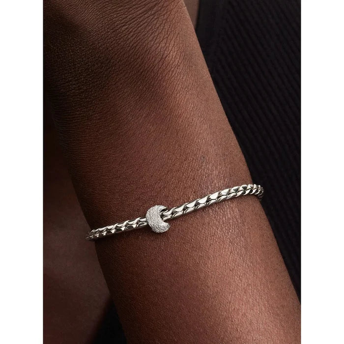 Pandora Textured Moon Mini Charm worn on a silver woven bracelet, displayed on a person’s wrist for scale and styling inspiration.