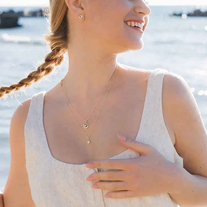 Smiling woman wearing wave shaped necklaces at sunny beach.