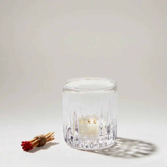 A clear glass candle holder features two candles, enhancing the decor with their soft illumination and elegant design.