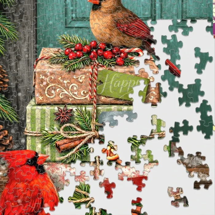 This Springbok Cardinal Couriers 500 Piece Jigsaw Puzzle features a fleet of bright red cardinal birds delivering mail across a snowy winter scene.