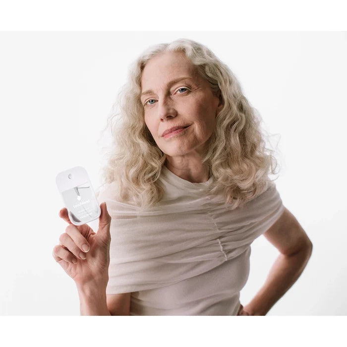 Woman holding touchland unscented hand sanitizer in a white background