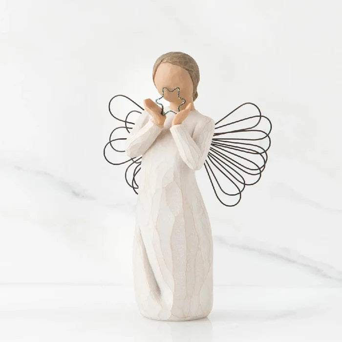A willow tree angel holding a heart, symbolizing love and serenity in a peaceful outdoor setting.