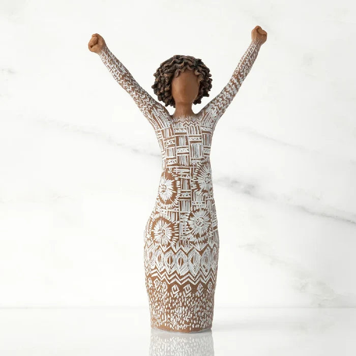 A figurine of a woman with her arms raised, expressing joy or celebration.