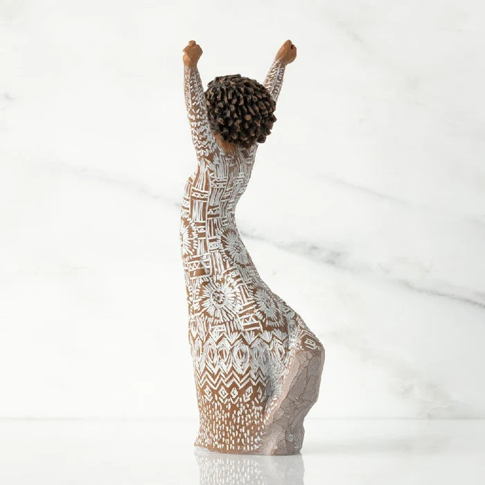 A decorative figurine depicting a woman with arms uplifted, symbolizing freedom or happiness.
