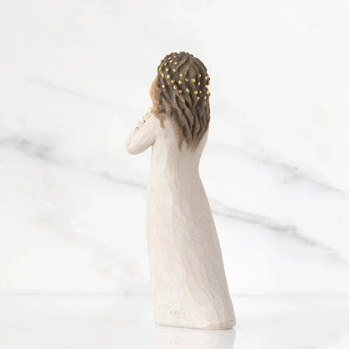 A figurine of a woman elegantly dressed in a flowing white gown, showcasing intricate details and graceful posture.