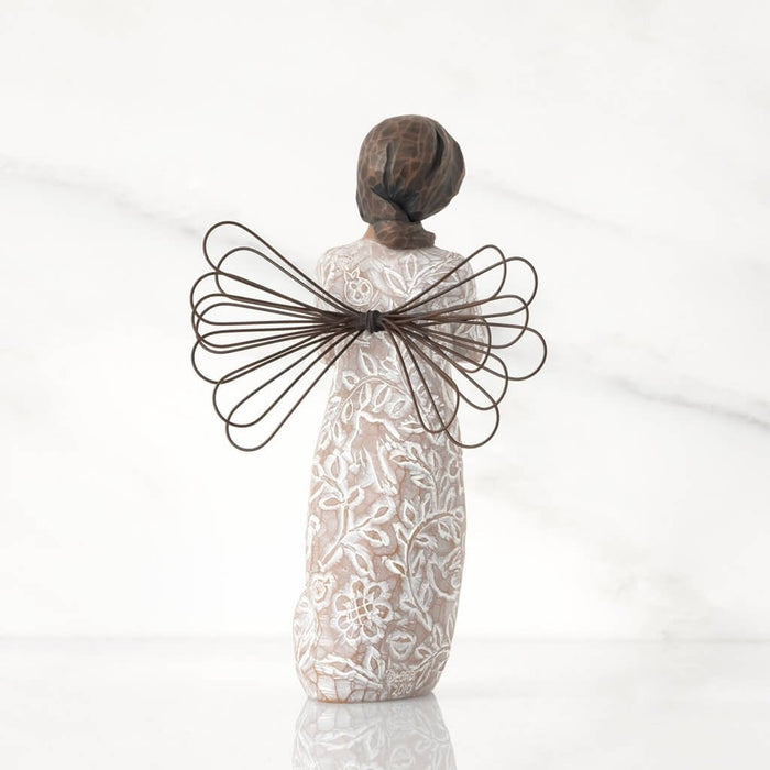 "Willow Tree Remembrance angel figurine with darker skin tone – hand-painted resin figure with floral design, wire wings, and gold heart for memory and healing."
