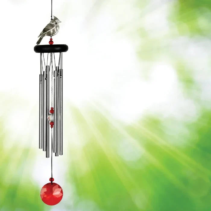 A red and white bird alongside a wind chime, enhancing the peaceful ambiance of the garden.
